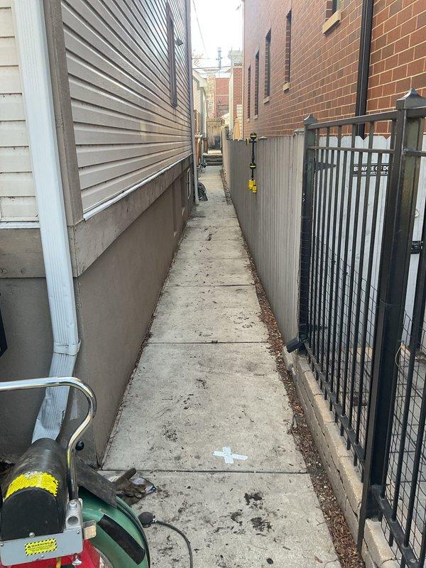 Responded to flooded drain concern located under deck area. Accessed service alleyway between residential structures to assess drainage system backup. Deployed equipment through narrow passageway to investigate standing water accumulation in subsurface drain line. Performed diagnostic evaluation of exterior drainage infrastructure and identified source of flooding condition.