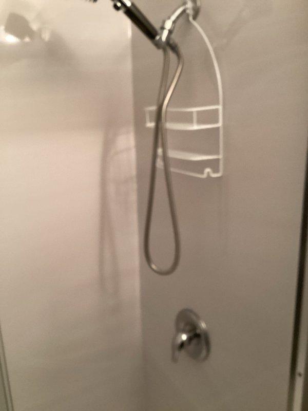 Work was cancelled by customer and rescheduled for future date. Site visit conducted and existing shower/tub installation photographed, showing chrome shower fixtures, handheld spray attachment, wall-mounted controls, and white fiberglass surround panels in serviceable condition.