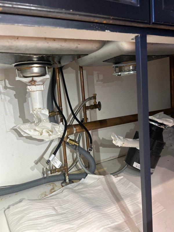 Successfully disconnected kitchen sink plumbing assembly to accommodate countertop replacement, then returned to reconnect all components upon completion of countertop installation. Disconnection included dual basin drain assemblies with basket strainers, P-trap configuration, garbage disposal unit, water supply lines with shut-off valves, and dishwasher drain connections. All chrome and brass fittings were carefully removed and protected during the countertop work. Upon reconnection, reinstalled all PVC drain piping, secured garbage disposal mounting, reconnected copper water supply lines with flexible supply hoses to shut-off valves, and reattached dishwasher drain lines to ensure proper drainage flow. Tested all connections for leaks and verified proper operation of both sink drains and garbage disposal unit.