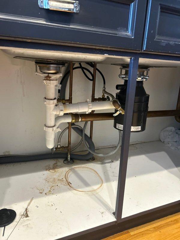 Successfully disconnected kitchen sink plumbing assembly to accommodate countertop replacement, then returned to reconnect all components upon completion of countertop installation. Disconnection included dual basin drain assemblies with basket strainers, P-trap configuration, garbage disposal unit, water supply lines with shut-off valves, and dishwasher drain connections. All chrome and brass fittings were carefully removed and protected during the countertop work. Upon reconnection, reinstalled all PVC drain piping, secured garbage disposal mounting, reconnected copper water supply lines with flexible supply hoses to shut-off valves, and reattached dishwasher drain lines to ensure proper drainage flow. Tested all connections for leaks and verified proper operation of both sink drains and garbage disposal unit.