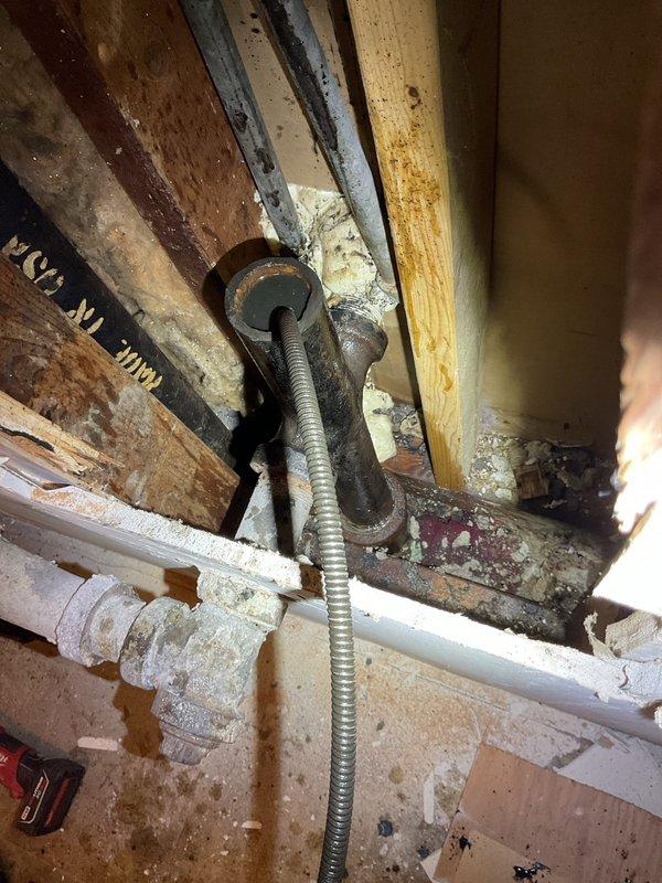 Responded to commercial plumbing service call for completely clogged sink with no drainage. Upon arrival, accessed the drain system beneath the fixture and inspected the vertical drain pipe, P-trap, and connection points. Cleared the obstruction from the drain line, restoring full drainage function. Inspected the plumbing assembly including the chrome P-trap fitting, vertical drain pipe, and floor connection boot for proper operation and potential leaks. Verified all connections were secure and tested the system to confirm water was flowing freely through the drain without backup or slow drainage issues.