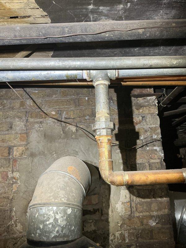 Completed commercial drain and sewer estimate inspection of basement utility area and bathroom facilities. Documented existing plumbing infrastructure including aged copper piping, PVC drainage lines, and ductwork showing deterioration and coating failure. Assessed bathroom fixtures under protective covering during renovation phase and evaluated exposed wall framing for future plumbing modifications.