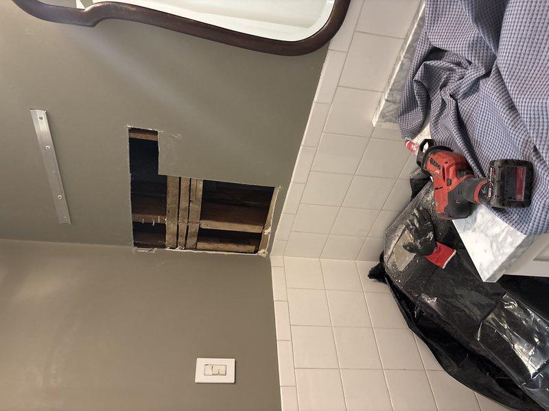 Performed plumbing repair work requiring building water shutdown during scheduled four-hour service window. Created ceiling access opening to reach overhead plumbing infrastructure, exposing floor joists to access multiple water supply lines including copper piping and PVC drain lines. Completed necessary repairs to piping system, with all lines properly secured using metal straps and hangers per code requirements.