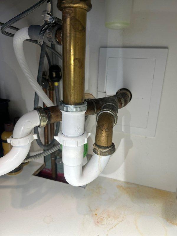 Responded to service call for multiple kitchen sink issues including loose faucet, under-sink leak, and noisy garbage disposal with excessive vibration. Upon inspection, secured loose faucet mounting hardware at deck plate. Identified leak at drain pipe connection beneath sink where PVC trap assembly meets copper tailpiece; tightened slip nut fitting and verified proper seal. Examined garbage disposal unit and found mounting bracket had loosened, causing unit to shake and amplify operational noise. Re-secured disposal mounting ring to sink flange with proper torque on mounting bolts. Tested all components by running water through faucet and operating disposal unit; confirmed no leaks present and disposal operates quietly without excessive movement. All plumbing connections tight and functioning properly.