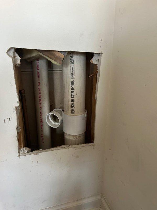 Accessed basement utility area and interior wall cavity to inspect and repair plumbing system components. Created access opening in drywall to reach concealed PVC drain and waste lines running vertically between wall studs. Evaluated copper supply lines, PVC drainage piping, and associated fittings for proper function and code compliance. Documented existing conditions of plumbing infrastructure, including pipe routing, connections, and integration with HVAC ductwork in unfinished basement space. Completed necessary repairs to restore proper drainage function and system integrity.