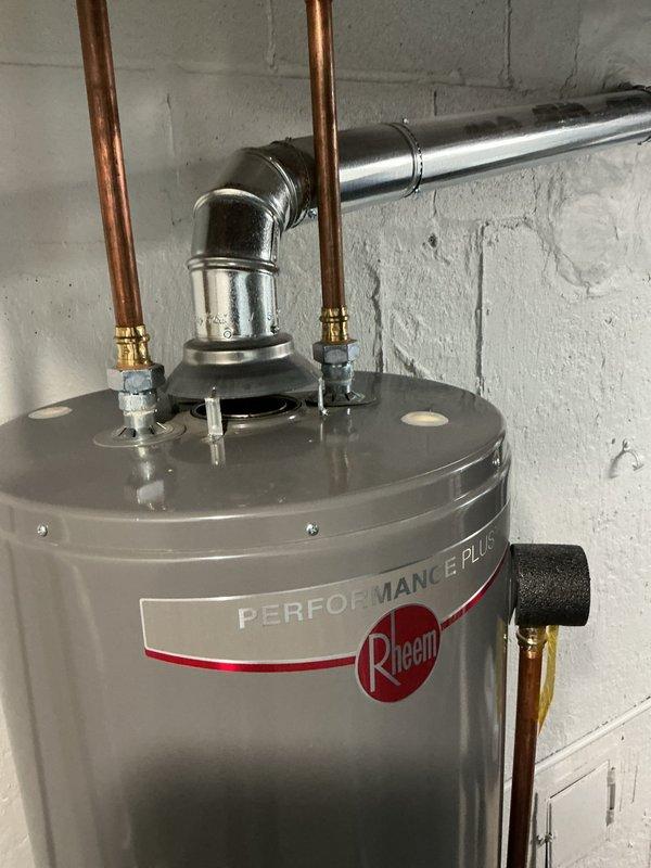 Responded to service call for grinding noise coming from recently installed Rheem Performance Plus tanked water heater. Upon arrival, inspected unit and confirmed hot water production was still operational. Performed diagnostic assessment of gas control valve, burner assembly, and internal components to identify source of grinding noise. Documented water heater condition with photos showing gas control valve with status light indicators, copper supply lines, brass fittings, and proper venting configuration. Unit appears properly installed with adequate clearances and professional plumbing connections.