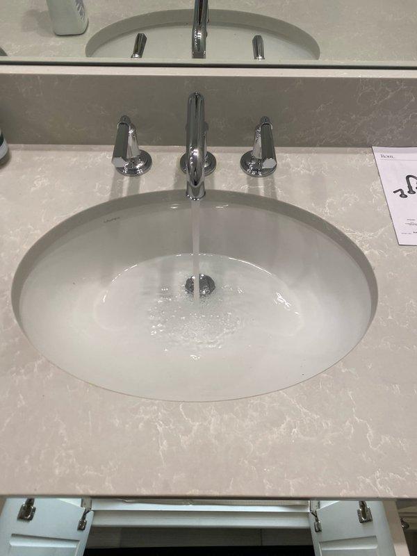Replaced existing bathroom faucet assembly with new three-piece chrome fixture including center spout and dual lever handles. Removed old faucet showing discoloration and staining around mounting holes, cleaned sink deck surface, and installed new fixture ensuring proper water flow and leak-free connections as verified during testing.
