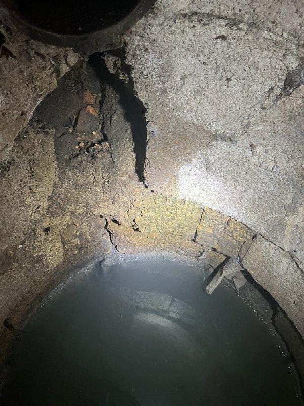 Responded to service call for catch basin repair estimate and inadequate hot water issue. Inspected deteriorated concrete catch basin area showing significant cracking, moisture damage, and standing water accumulation indicating drainage problems. Documented R.A. Williams Co. sewage access cover and surrounding concrete with visible structural deterioration requiring repair. Assessed hot water system in secondary building reporting insufficient temperature output.