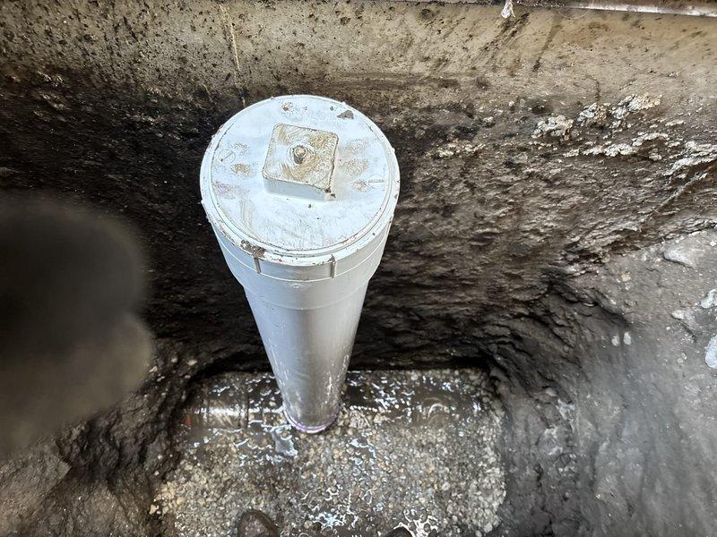 Completed plumbing repair work in confined crawlspace area with deteriorated structural conditions and moisture damage. Accessed and serviced underground utility cylinder with conical top assembly in basement area showing signs of water intrusion. Documented existing conditions including compromised wooden structural elements and moisture presence around plumbing fixtures for repair assessment and future maintenance planning.
