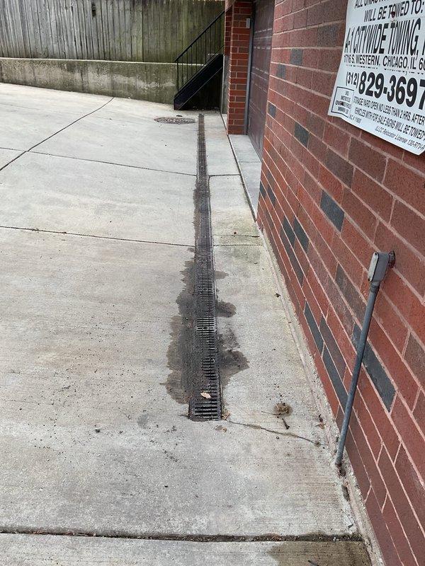 Inspected and cleaned trench drain system running along commercial building exterior and patio area. Trench drain was successfully cleared of debris and verified to be flowing properly. Scheduled follow-up service with vector truck to perform hydro-jetting and rodding of connected storm basin to ensure complete drainage system functionality.