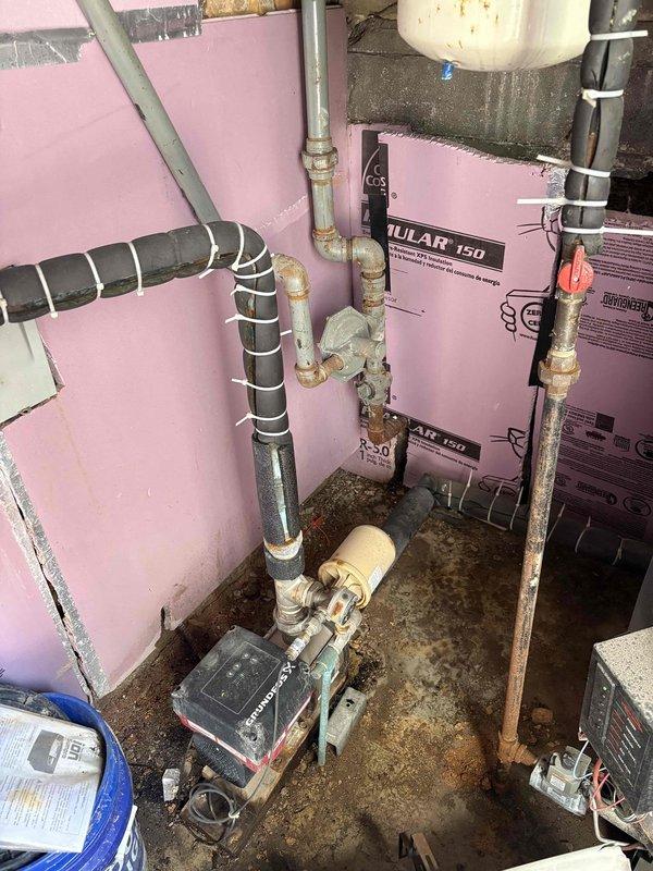 Responded to service call for leaking pipe located under front stairs. Upon inspection, identified corroded copper piping in utility area with visible water damage on floor surfaces and deteriorated pipe insulation. Assessed plumbing system including circulator pump, brass fittings, and associated copper supply lines showing significant age-related corrosion and weathering. Documented existing conditions including compromised foam insulation, corroded mounting hardware, and moisture infiltration in mechanical space. Provided comprehensive estimate for pipe repair and replacement of affected components to resolve active leak and prevent further water damage.