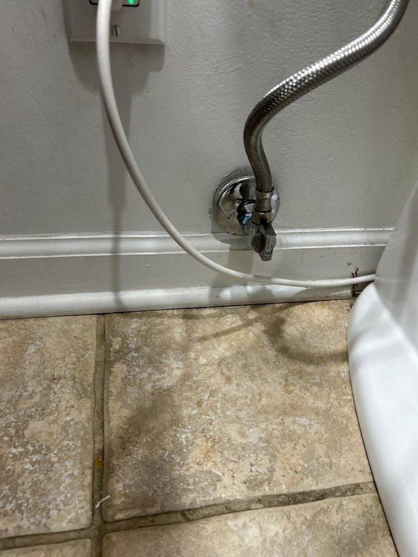 Completed building shut down plumbing repair involving under-sink installation with new chrome P-trap assembly, flexible braided stainless steel supply lines with brass connectors, and wall-mounted shut-off valves with chrome escutcheons. Installed garbage disposal connection components including black plastic discharge fitting with threaded chrome collar, ensuring proper drainage configuration and secure mounting to cabinet backing. All chrome fixtures installed without corrosion, supply lines properly connected to wall-mounted valves, and electrical connections completed with visible power indicator for disposal unit operation.