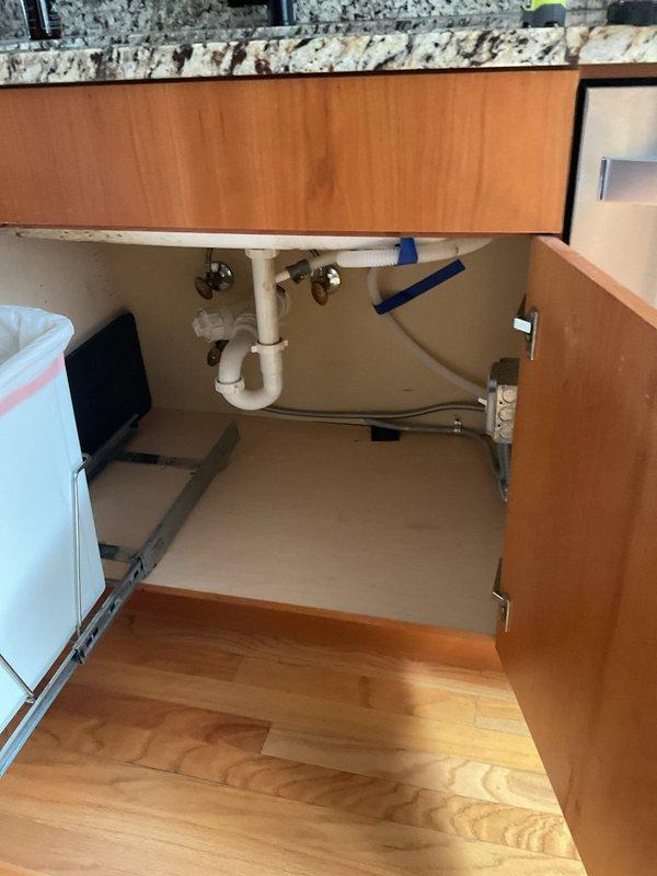Provided estimate for installation of new garbage disposal unit under kitchen sink where no disposal previously existed. Assessed existing plumbing configuration including P-trap assembly, drain lines, and water supply connections to determine requirements for disposal installation. Photographed current under-sink conditions showing standard PVC drain piping and shut-off valves to document pre-installation setup and plan necessary modifications to accommodate new disposal unit.