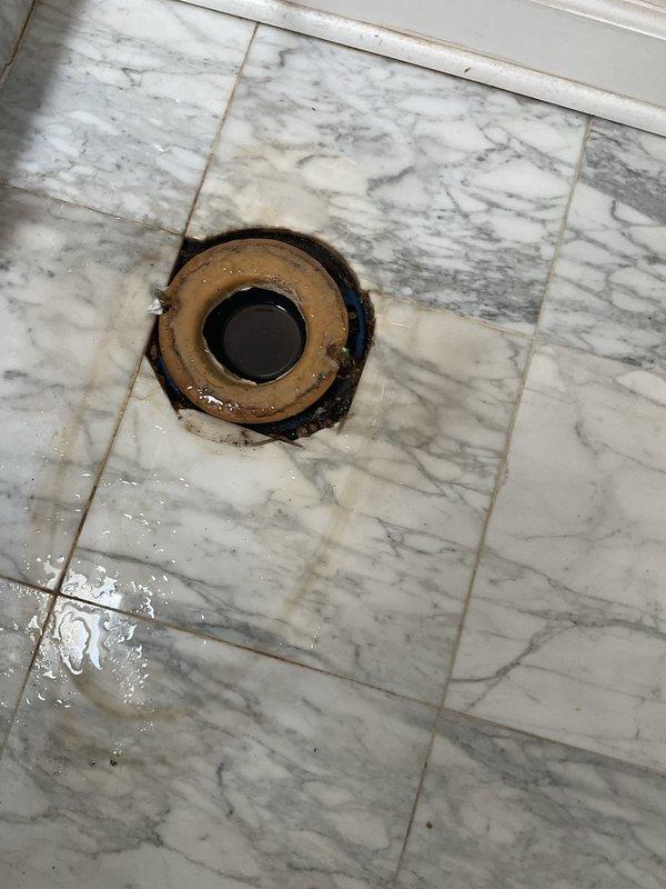 Responded to emergency call for water intrusion from second floor bathroom into dining room below, caused by backed-up bathtub drain. Upon arrival, inspected second floor bathroom and identified standing water in tub with floor drain showing signs of overflow, evidenced by dark staining and water damage around drain flange on marble tile flooring. Assessed ceiling damage in dining room directly below affected bathroom, noting water penetration through tray ceiling structure. Cleared main drain blockage causing backup, restoring proper drainage function to bathtub and floor drain. Verified water flow and confirmed no further leakage into lower level upon completion of drain clearing.