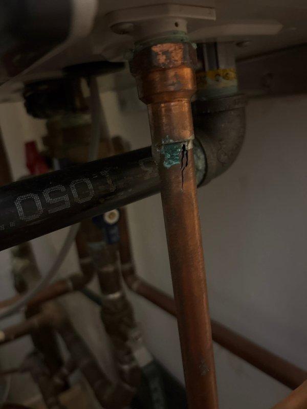 Inspected water heater plumbing system and documented existing conditions. Identified significant corrosion on copper supply pipes with green verdigris formation at connection points and brown oxidation along pipe surfaces, indicating prolonged moisture exposure and aging infrastructure. Photographed corroded vertical copper pipe connections, valve assemblies including blue and green-handled ball valves with brass fittings, and black flexible supply line. Customer approved proceeding with necessary repairs and will submit payment authorization form for processing.