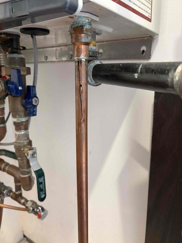 Inspected water heater plumbing system and documented existing conditions. Identified significant corrosion on copper supply pipes with green verdigris formation at connection points and brown oxidation along pipe surfaces, indicating prolonged moisture exposure and aging infrastructure. Photographed corroded vertical copper pipe connections, valve assemblies including blue and green-handled ball valves with brass fittings, and black flexible supply line. Customer approved proceeding with necessary repairs and will submit payment authorization form for processing.