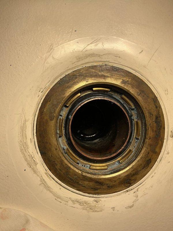 Conducted diagnostic assessment of bathroom sink drain assembly showing significant age-related deterioration. Identified tarnished brass/bronze drain fitting with visible corrosion, mineral deposits, and oxidation requiring replacement. Licensed plumber scheduled to return to perform complete drain assembly replacement and restore proper fixture function.