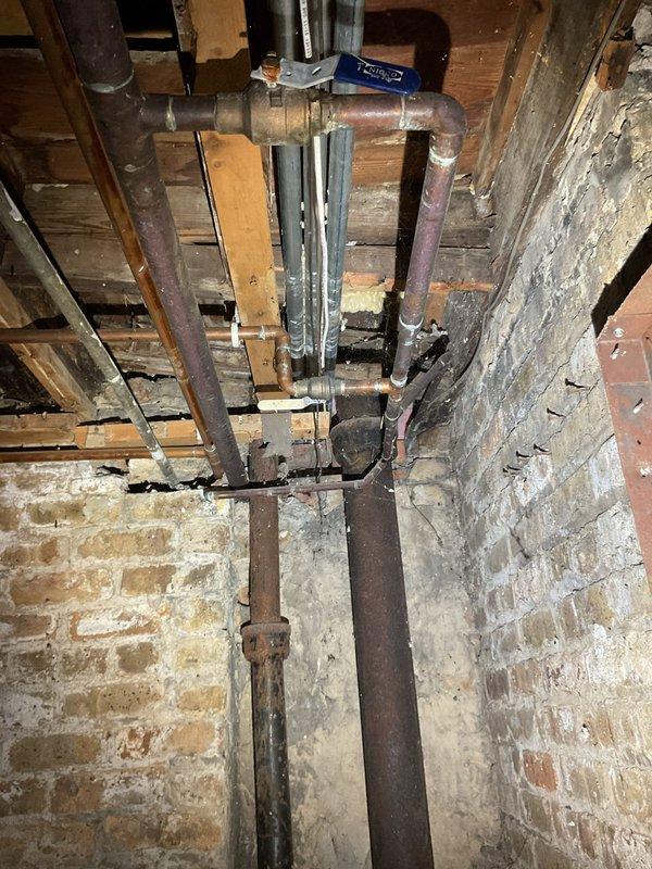 Responded to tenant complaint of bathtub backing up in one of the residential units at a multi-level commercial property. Conducted video inspection of the main sewer line to diagnose recurring backup issues reported by the occupant. Documentation revealed aging plumbing infrastructure with mixed pipe materials including copper and galvanized metal showing significant corrosion, oxidation, and deterioration throughout the exposed basement/crawl space areas. Inspection identified potential contributing factors to frequent main line blockages within the building's drainage system.