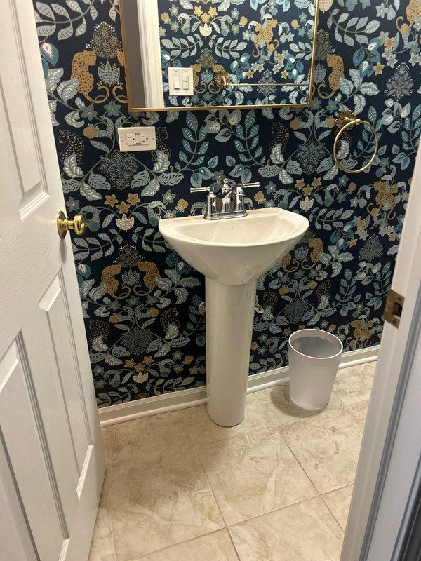 Installed new chrome two-handle faucet fixture on white pedestal sink in residential powder room. Replaced existing faucet with traditional-style unit featuring separate hot and cold water lever handles and curved spout, ensuring proper mounting, water supply connections, and leak-free operation upon completion.