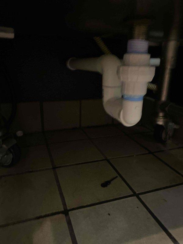 Replaced existing drain assembly with new PVC piping and proper trap configuration beneath sink fixture. Installed white PVC P-trap assembly with appropriate threaded fittings and connections, including blue gasket seal to ensure watertight operation. All components were secured with proper PVC connections per code requirements to restore functional drainage system.