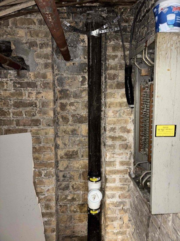 Installed clean out fitting on existing vertical drain stack in basement utility area with exposed brick masonry. Rodded drainage line to clear obstruction and restore proper flow. Clean out provides accessible access point for future maintenance of the plumbing system.
