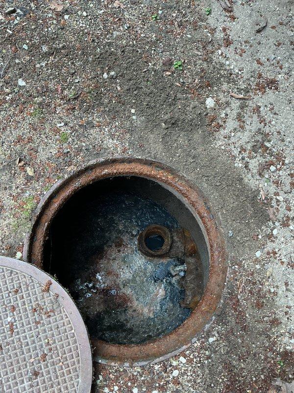Responded to service call regarding intermittent rotten egg odor emanating from recently installed sump pump system located in nursery. Conducted thorough inspection of sump pump installation, basin seal integrity, and discharge piping system. Examined vertical PVC discharge line with mounting brackets, basin cover seal, and check valve operation to identify potential sources of sulfur smell. Inspected exterior discharge point and observed significant corrosion on metal components at grade-level termination point. Verified proper trap configuration and ventilation to prevent sewer gas backflow into living space. Assessed basin for standing water conditions that could promote anaerobic bacterial growth causing hydrogen sulfide odor. Confirmed system operational functionality and seal integrity to ensure no safety hazards present for occupants.