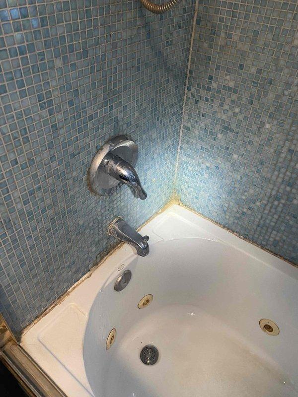 Assessed bathroom plumbing system and identified deteriorated piping under sink requiring replacement due to advanced rust and poor structural condition. Documented existing shower system with dual chrome showerheads and jetted bathtub installation, noting significant discoloration and staining along tub-to-tile interface indicating potential moisture intrusion or caulking failure. Provided photographic documentation of conditions and prepared estimate for necessary piping replacement work.