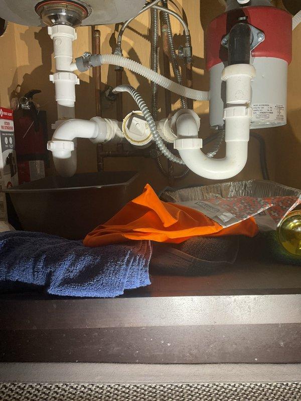 Responded to service call for non-functioning garbage disposal with water pooling under kitchen sink. Upon inspection, found garbage disposal unit inoperable and confirmed standing water accumulation in cabinet base. Assessed complete under-sink plumbing configuration including PVC P-trap assembly, discharge lines, and drainage connections. Diagnosed disposal failure and identified compromised drain seal at disposal mounting flange contributing to leak. Removed defective garbage disposal unit, cleared obstruction from drain line, and inspected all pipe connections for integrity. Installed replacement disposal unit with new mounting assembly and gasket, reconnected discharge pipe to existing PVC trap system, and verified proper alignment of all drainage components. Tested system operation under full water flow, confirmed disposal motor function, and verified complete elimination of leakage. Cleaned work area and removed all debris from cabinet interior.