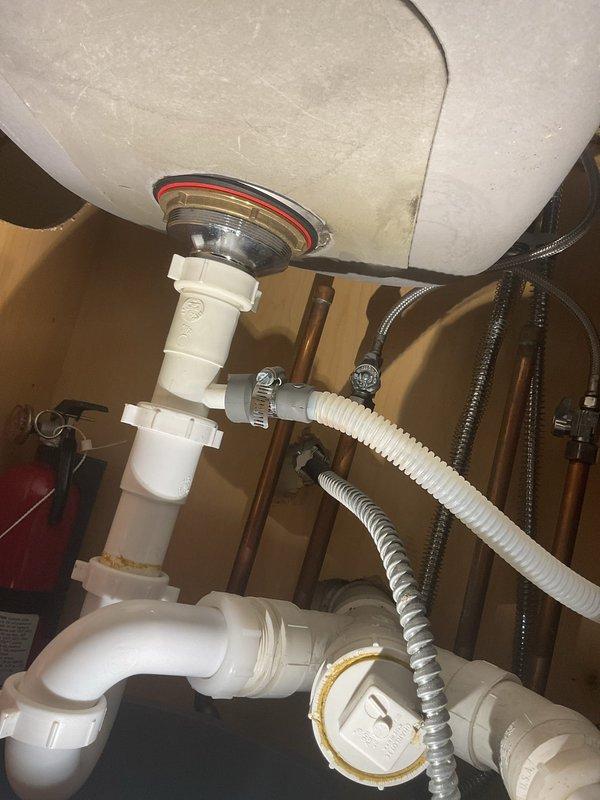 Responded to service call for non-functioning garbage disposal with water pooling under kitchen sink. Upon inspection, found garbage disposal unit inoperable and confirmed standing water accumulation in cabinet base. Assessed complete under-sink plumbing configuration including PVC P-trap assembly, discharge lines, and drainage connections. Diagnosed disposal failure and identified compromised drain seal at disposal mounting flange contributing to leak. Removed defective garbage disposal unit, cleared obstruction from drain line, and inspected all pipe connections for integrity. Installed replacement disposal unit with new mounting assembly and gasket, reconnected discharge pipe to existing PVC trap system, and verified proper alignment of all drainage components. Tested system operation under full water flow, confirmed disposal motor function, and verified complete elimination of leakage. Cleaned work area and removed all debris from cabinet interior.