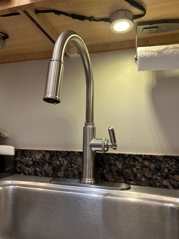 Installed customer-supplied kitchen faucet with pull-down spray head in brushed stainless steel finish. Connected braided supply lines to existing shut-off valves beneath sink and secured all plumbing connections. Verified proper operation of single-lever handle and spray function, ensuring no leaks at mounting points or supply connections.