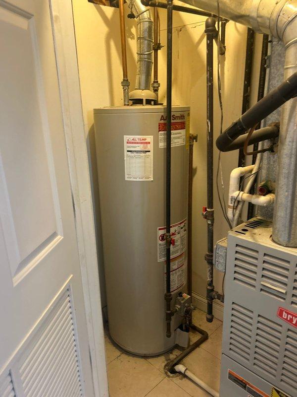 Conducted plumbing estimate for water heater replacement at residential property. Inspected existing 50-gallon water heater approximately 20 years old, which is currently operational but nearing end of service life. Documented existing installation in utility room, including copper and black pipe connections at top of unit, proximity to HVAC equipment, and overall configuration of mechanical space. Noted evidence of water staining on walls and ceiling near ductwork, indicating previous or ongoing moisture intrusion issues that should be addressed during replacement. Photographed current water heater setup, utility room layout, and surrounding plumbing connections to prepare accurate replacement estimate for new homeowners seeking proactive equipment upgrade.