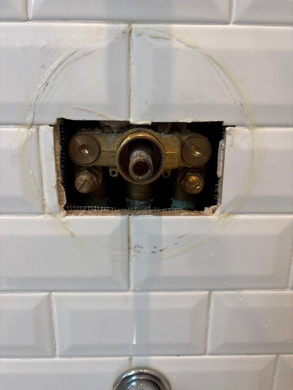 Responded to morning appointment for shower cartridge replacement. Upon inspection, found existing valve assembly with brass components showing age-related wear and mineral deposits. Successfully removed old cartridge from wall-mounted shower/tub control valve, replaced with new cartridge, and reassembled chrome fixtures including temperature control handles and diverter valves. Verified proper water flow and temperature control operation through handheld shower attachment and tub spout. System tested and restored to full functionality.