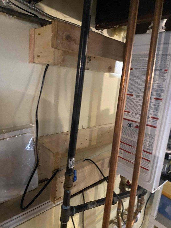 Responded to warranty service call for plumbing system inspection in mechanical space. Upon arrival, evaluated pressure relief valve assembly and associated piping connections mounted beneath floor joists, including cast iron elbow fitting with brass valves and copper piping configuration. Documented existing plumbing infrastructure showing aged copper lines with sensor wiring secured along pipe runs, connected to water heating appliance. Captured photographic documentation of installation for warranty assessment and coordination with management team for appropriate technician assignment and follow-up action.
