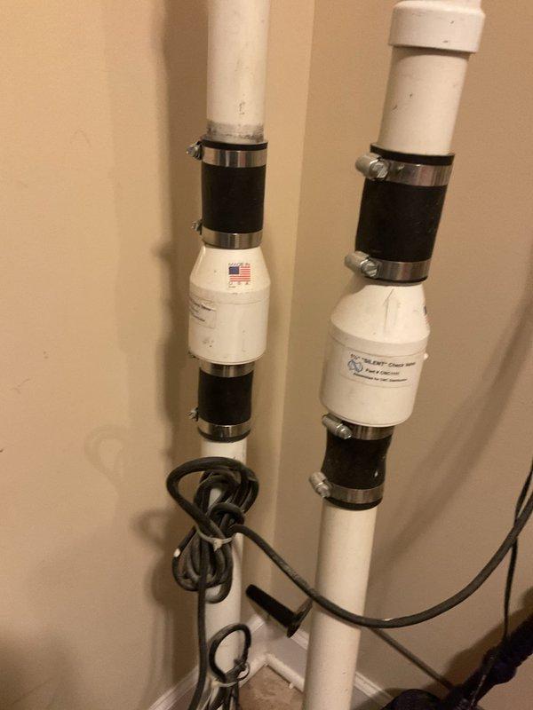 Completed plumbing inspection revealing aged copper piping system with significant corrosion and verdigris buildup at connection joints, along with assessment of dual vertical PVC drainage pipes equipped with rubber couplings and sensor cables. Documented existing conditions and scheduled installation work to address system concerns.