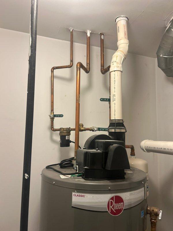 Responded to a leaking water heater emergency in a basement utility area. Upon inspection, identified active leaks originating from the top and side connections of a 10-year-old Rheem Classic 50-gallon natural gas water heater (Model PRO50G-42N RH67 PV, manufactured July 2014). Assessed all copper supply line connections, brass fittings, and top-mounted valves for failure points. Documented existing plumbing configuration including copper water lines and white PVC venting system. Photographed unit specifications, warning labels, and overall installation setup for service records and replacement recommendations.
