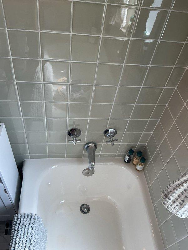 Conducted on-site assessment for bathtub replacement project involving removal of existing white corner-installed tub and installation of client-provided replacement unit. Evaluated current fixture configuration including chrome-finished spout and dual cross-handle faucets mounted on tiled wall, verified drain assembly accessibility, and assessed surrounding tile work condition to determine removal approach and potential wall repair requirements.