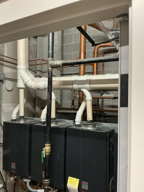 Responded to emergency service call for leaking Rinnai tankless water heater. Upon arrival, inspected unit and associated plumbing connections including copper supply lines, brass fittings, and shut-off valves. Documented existing installation configuration showing unit mounted with digital display operational at 148°F, along with connected expansion tank and filtration system. Assessed mechanical room environment containing multiple heating units and venting infrastructure to determine source of leak and appropriate repair approach.
