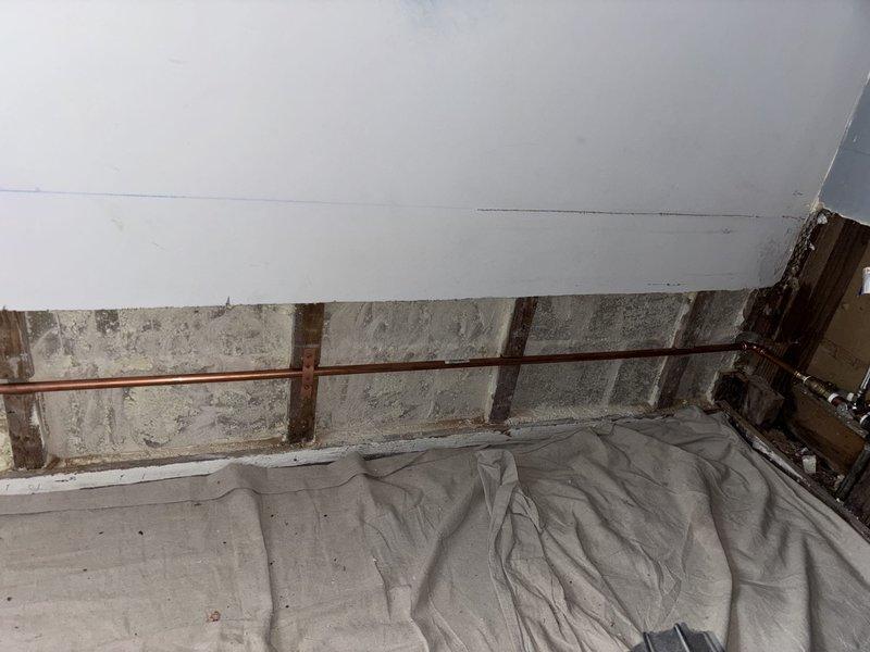 Inspected and documented plumbing conditions for proposed repair work in basement crawl space and exterior hose bib location. Interior assessment revealed copper supply line running along concrete block foundation wall with protective floor covering in place for ongoing work area. Exterior evaluation identified aged brick wall with weathered mortar joints, visible cracking, and existing outdoor spigot fixture with cross-handle valve requiring attention. Comprehensive photographic documentation completed to support repair proposal and scope of work recommendations.