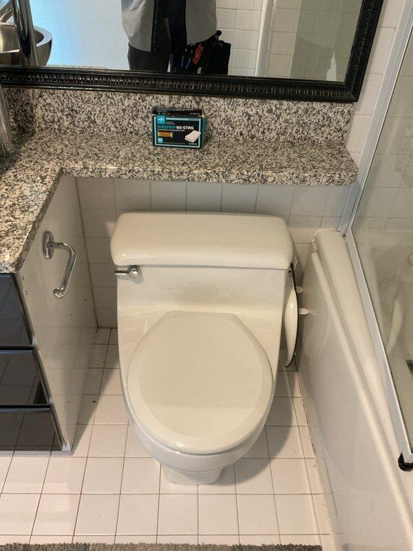 Responded to service call for toilet leaking at base. Upon inspection, identified water seepage occurring at the connection point between the toilet bowl and floor flange. Assessed the wax ring seal and mounting bolts for failure. The existing seal showed signs of deterioration and compression, allowing water to escape during flush cycles. Documented existing conditions with photographs showing the one-piece toilet installation, chrome shut-off valve, braided supply line, and tile flooring surrounding the fixture. Presented repair options to address the leak, including removal and resetting of the toilet with new wax ring, replacement of closet bolts, and verification of proper flange condition.