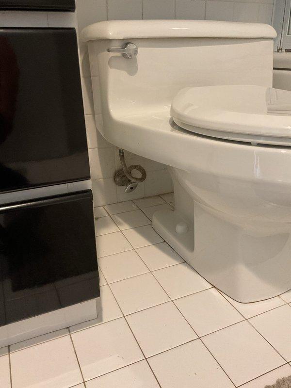 Responded to service call for toilet leaking at base. Upon inspection, identified water seepage occurring at the connection point between the toilet bowl and floor flange. Assessed the wax ring seal and mounting bolts for failure. The existing seal showed signs of deterioration and compression, allowing water to escape during flush cycles. Documented existing conditions with photographs showing the one-piece toilet installation, chrome shut-off valve, braided supply line, and tile flooring surrounding the fixture. Presented repair options to address the leak, including removal and resetting of the toilet with new wax ring, replacement of closet bolts, and verification of proper flange condition.