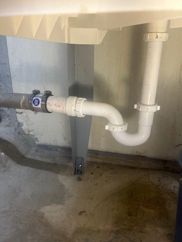 Responded to service call for disconnected utility sink P-trap requiring repair or replacement. Upon inspection, found the white PVC P-trap assembly had separated from the drainage system, causing potential water leakage issues. Successfully reconnected and secured the P-trap assembly to the vertical drain pipe, ensuring proper alignment and watertight seal at all connection points. Verified trap configuration maintains proper water seal to prevent sewer gas infiltration. Tested drainage system for leaks and confirmed proper flow through the reassembled P-trap and connecting pipes. System restored to full operational status with no active leaks detected.