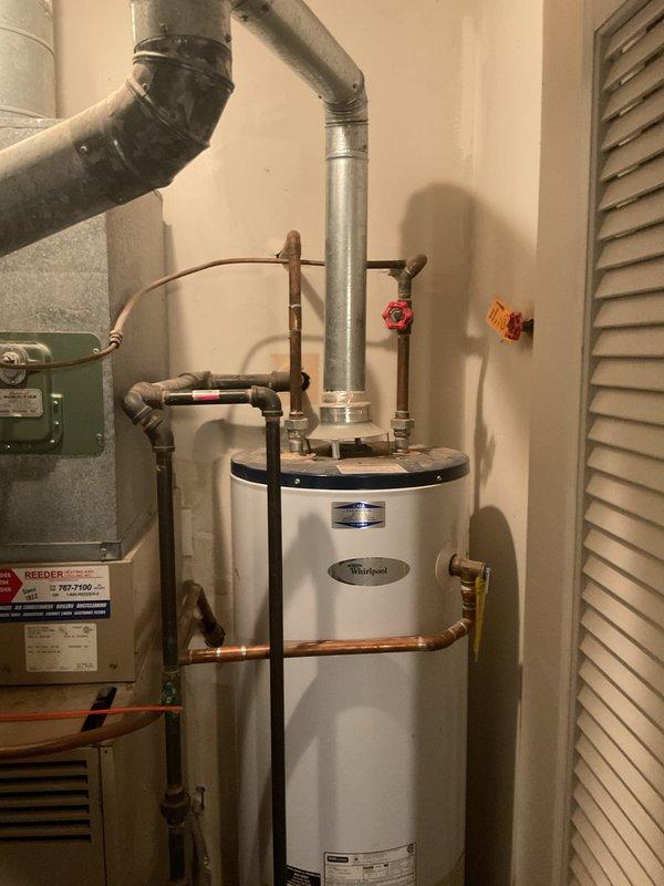Completed on-site assessment of residential water heating system due to loss of hot water. Inspected existing white Whirlpool tank-style water heater located in utility room, noting all plumbing connections, gas supply lines, venting configuration, and seismic strapping. Documented shut-off valve locations including red and yellow handled valves on supply lines, copper piping connections, and metallic vent pipe with 90-degree elbow configuration. Evaluated clearances around unit in relation to adjacent York HVAC equipment and confirmed accessibility for replacement. Photographed current installation including all pipe routing, electrical connections visible via wall-mounted green panel, and proper seismic restraint strapping. Provided comprehensive estimate for complete water heater replacement including removal and disposal of existing unit, installation of new tank-style water heater with code-compliant connections, and all necessary materials and labor.