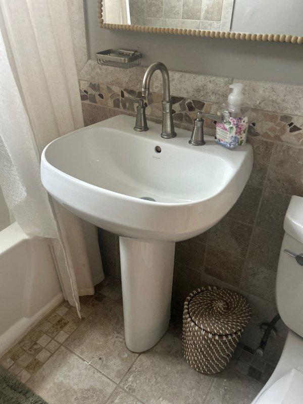 Conducted comprehensive plumbing assessment for pedestal sink replacement and leaking bathtub faucet repair. Inspected existing copper supply lines, brass shut-off valves, and flexible braided connections under current sink installation, noting age-related tarnishing and minor corrosion on valve components. Evaluated bathroom fixture configuration including white pedestal sink with brushed nickel faucet assembly and surrounding tile work to provide accurate estimate for replacement and repair services.