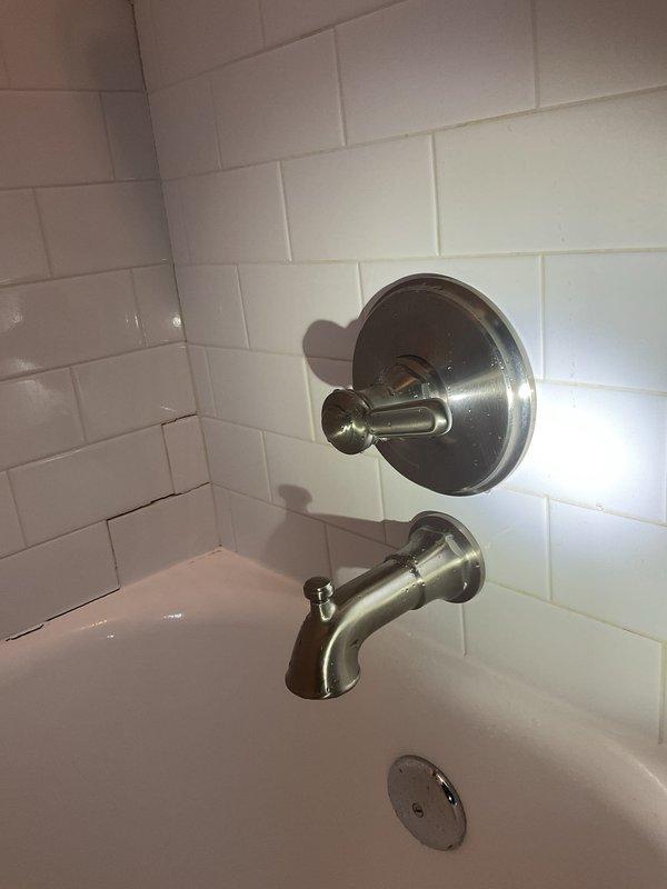 Responded to low hot water pressure complaint affecting single shower in second-floor unit of century-old residential property. Inspected bathroom fixtures including tub/shower valve assembly with brushed nickel finish and standard lever-style control mechanism mounted on subway tile surround. Assessed water flow from tub spout and shower diverter, examined valve cartridge operation, and checked for potential sediment buildup or mineral deposits restricting hot water delivery. Documented existing fixture condition showing normal wear consistent with age and mineral exposure. Investigated potential causes including partially closed shutoff valves, corroded galvanized supply piping common in older properties, faulty mixing valve cartridge, or sediment accumulation in hot water lines from basement-located water heaters serving the building.