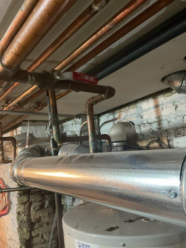 Responded to water leak complaint affecting unit below. Performed comprehensive leak detection inspection of plumbing system infrastructure. Investigated exposed copper piping showing significant oxidation and aging throughout basement mechanical room. Examined multiple pipe runs, ductwork, and connections for signs of active leakage or moisture intrusion. Documented extensive rust staining and discoloration on surrounding walls indicating historical moisture exposure. Inspected water heater installation and associated piping. Assessed HVAC system components and air handler unit revealing substantial debris accumulation and potential condensate drainage concerns. Photographed all findings for documentation purposes with both units accessible as requested.