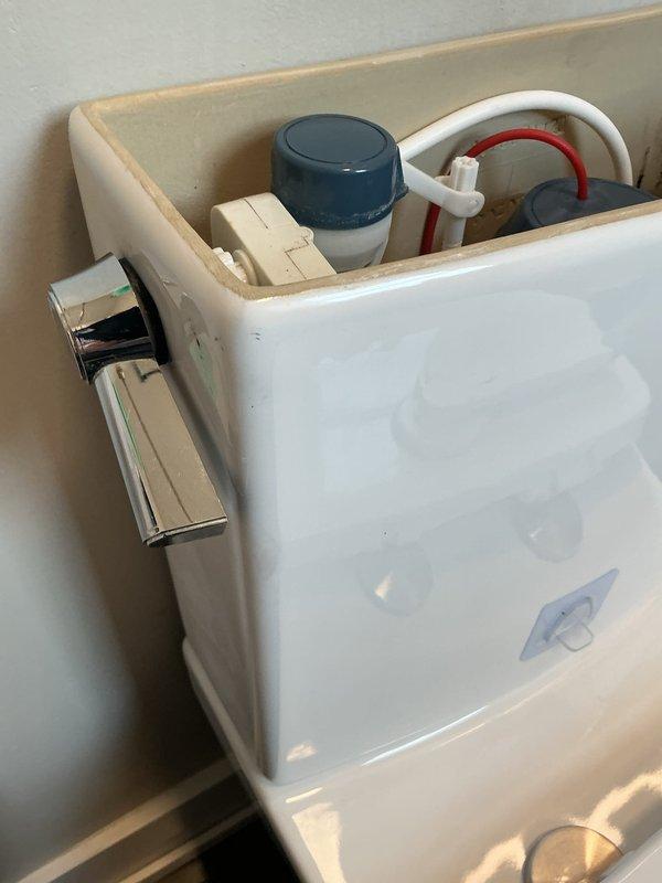 Responded to report of toilet leaking from tank connection point. Upon inspection, identified leak originating from compromised tank-to-bowl mounting hardware at right rear position. Removed toilet tank lid to assess internal components and verify no additional issues with fill valve, flush valve, or associated mechanisms. All internal components including fill valve assembly, overflow tube, and flush valve were found to be in normal operating condition. Tightened tank mounting bolt and coupling nut at affected location to restore proper seal and eliminate active leak. Verified repair by checking for moisture and confirming secure connection at all tank mounting points.
