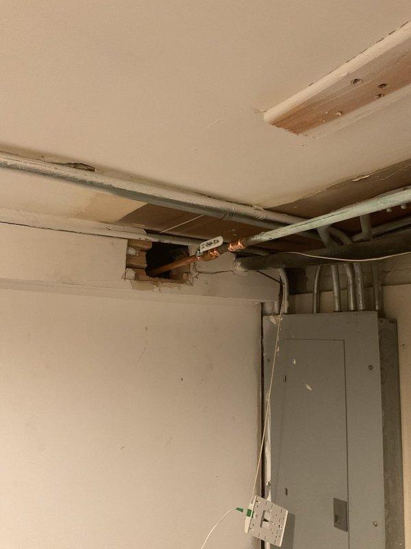 Responded to report of outdoor spigot leaking when operated from both exterior and interior shut-off locations. Accessed interior wall cavity to locate and diagnose the source of the leak in the supply line feeding the exterior hose bib. Created access opening in basement utility area wall to expose copper piping and valve assembly for inspection and repair.