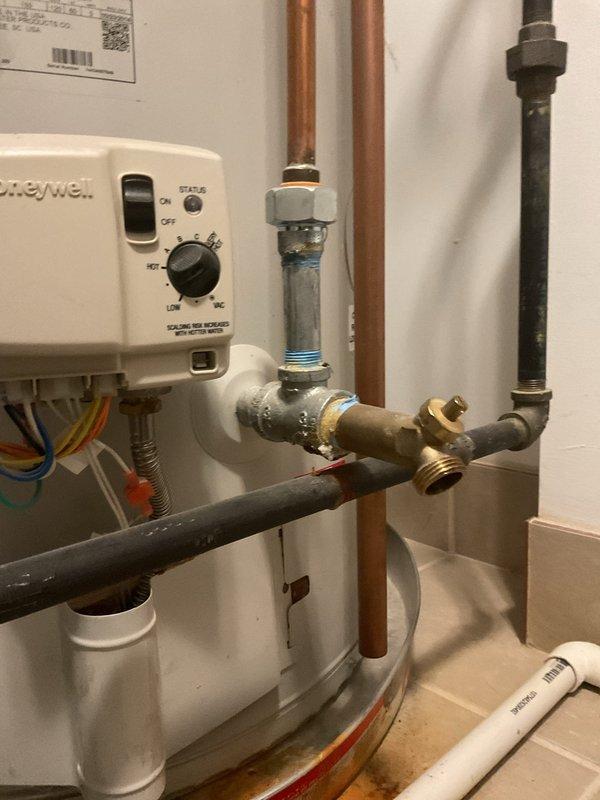 Responded to service call for water heater leaking from pipe at bottom of tank. Upon inspection, identified leak originating from threaded connection at base of unit. Assessed entire plumbing assembly including copper supply lines, brass fittings, dielectric unions, and circulation pump mounted atop water heater. Tightened leaking connection and verified integrity of all pipe joints, valves, and fittings throughout the system. Inspected PVC venting, circulation pump operation, and Honeywell control unit for proper functionality. Tested system under pressure to confirm leak was resolved and all connections remained secure with no further water discharge detected.