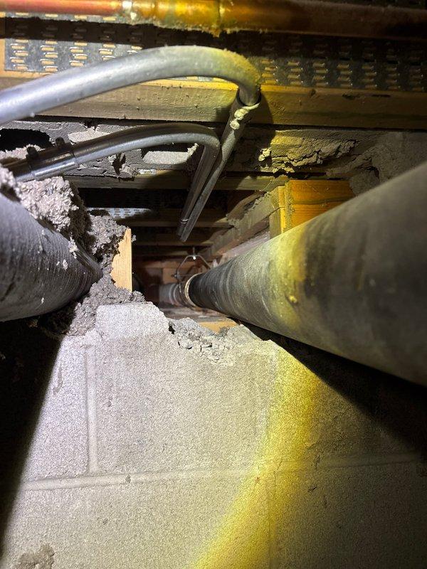 Completed plumbing repair work in crawl space area involving deteriorated copper piping showing significant corrosion and mineral deposits. Protected work areas in unit 2 pantry and storage unit with plastic sheeting as planned. Addressed compromised concrete flooring near mechanical systems where cracking and structural deterioration were evident, with exposed underlayment and damaged foundation edges requiring attention during the repair process.
