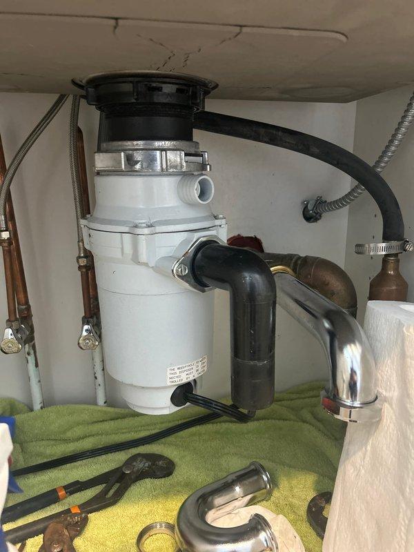 Responded to service call for kitchen sink leak underneath cabinet. Upon inspection, identified leak originating from garbage disposal connections and P-trap assembly. Disassembled and inspected disposal mounting flange, drain connections, and trap piping. Replaced worn gaskets and seals at disposal discharge connection. Tightened all slip-joint connections on chrome P-trap assembly and verified proper alignment of drain piping. Tested system by running water through sink and operating garbage disposal unit to confirm leak was resolved and all connections were secure with no further dripping.